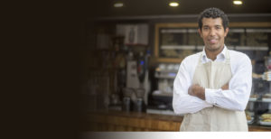 Business Savings image: Young African American business man in front of his coffee shop